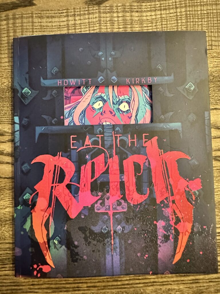 Eat The Reich cover, depicting a vampire commando inside a drop coffin, with only part of their face visible through a slit in the box. The slit in the box is a cutout, with the vampire peering in from the page underneath, creating a three dimensional effect. If you open the flap, you can see the inside of the coffin cover, as well as a full body image of the vampire inside. It's very immersive.