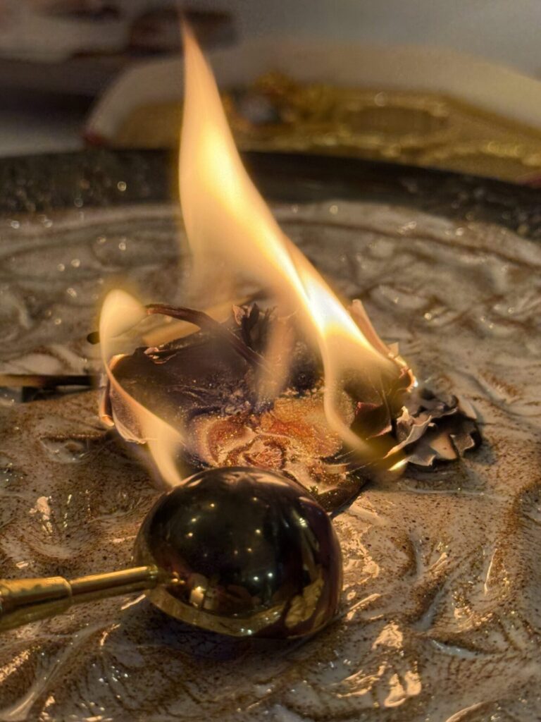 Paper, sealing wax, and berries burning on a ceramic plate.